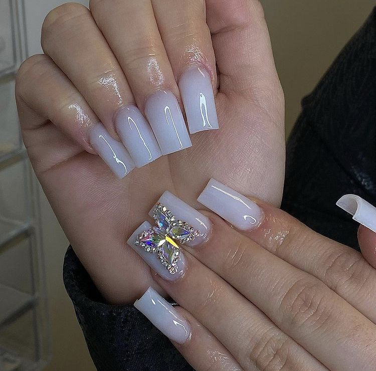 Short white coffin nails with a jeweled butterfly