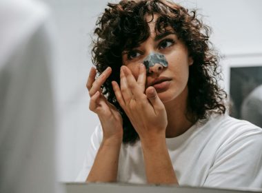 curly woman applying nose strip in bathroom