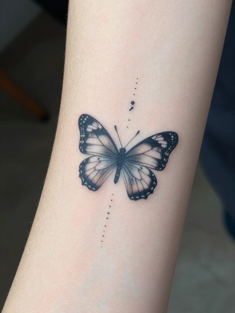"Macro shot of a forearm: a small butterfly Tattoo followed by a faint dotted line that ends in a bold semicolon just behind its wings. Clean skin, symbolic narrative focus."