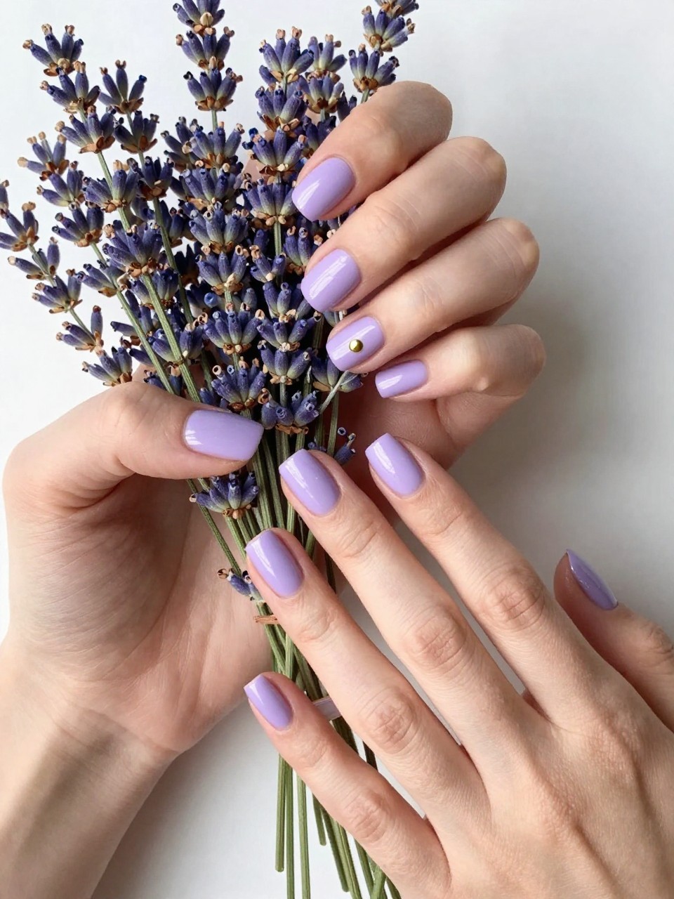 Overhead shot of hands arranging a bunch of fresh lavender. The short, square nails are an opaque pastel lavender. A single, perfect gold dot sits at the base of each nail. The morning light is soft and luminous.