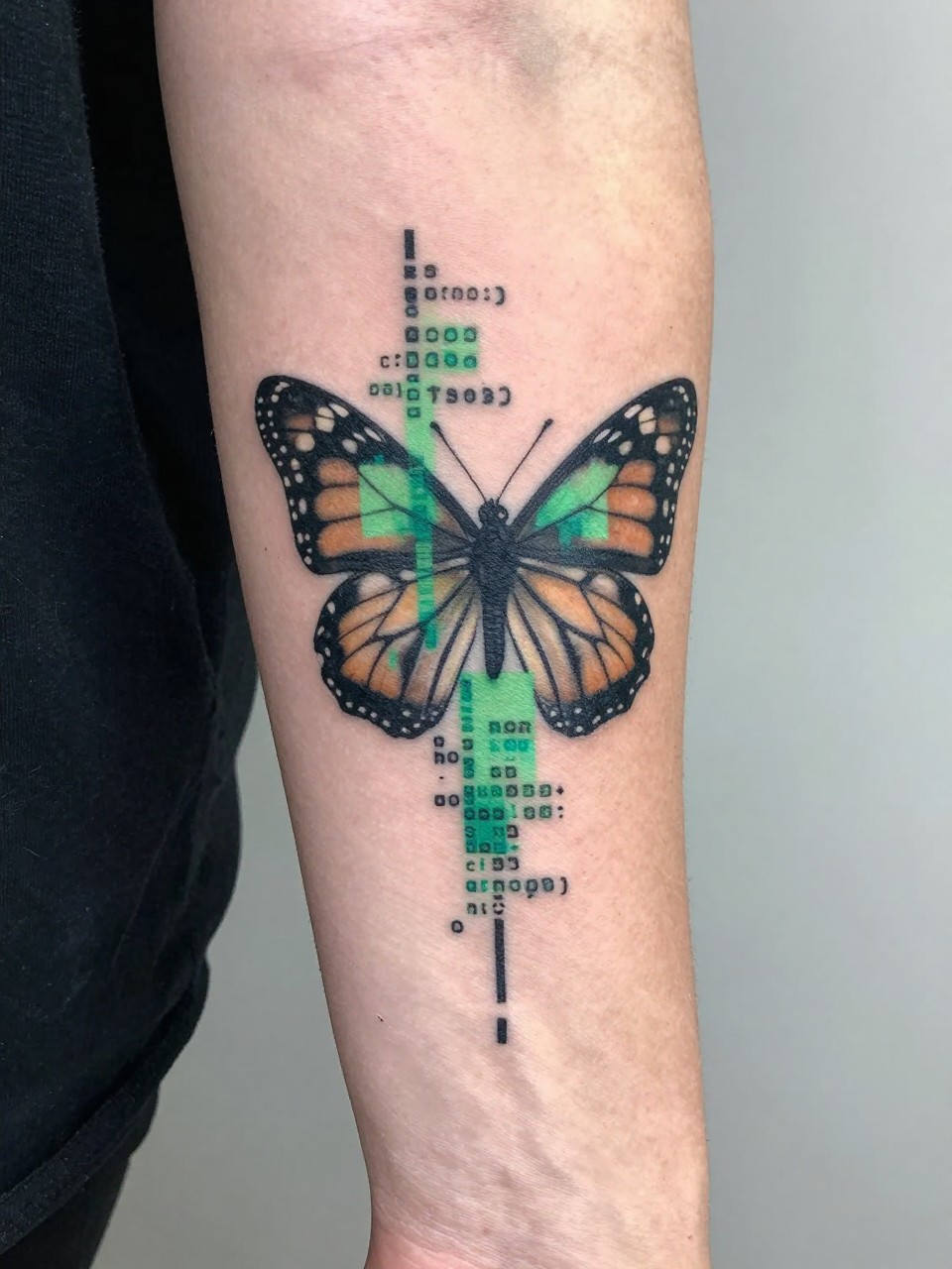 "Forearm close-up: a monarch butterfly tattoo with a large section glitching into green-tinted pixels and code. Clean skin contrasts the digital disintegration effect."