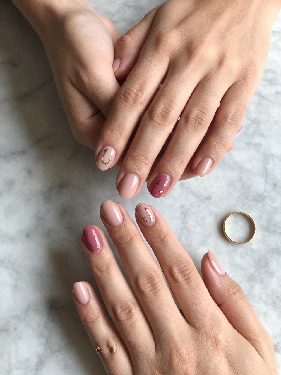 90-degree overhead top-down view of two feminine hands with oval medium nails.
The manicure features a dusty rose base with thin gold western-inspired line art including stars and horseshoes on two accent nails.
Include glossy gel finish.

Hands are posed one hand resting gently over the other.

Scene set on a marble surface with a small gold ring nearby.

Bright natural daylight with soft shadows, hyper-realistic lifestyle photography, sharp focus on nails, natural skin texture, realistic hands, no extra fingers.