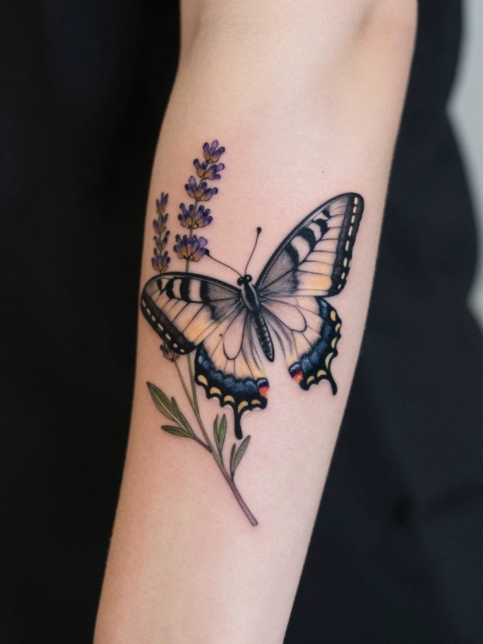 "Detailed view of a forearm tattoo where a swallowtail butterfly is nestled among finely detailed lavender stems and leaves. The composition wraps elegantly around the arm. Soft, natural light."