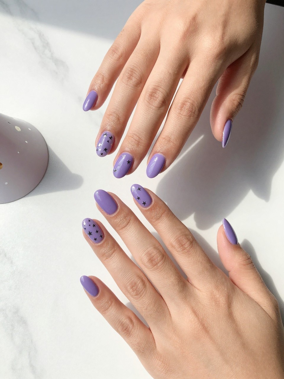 90-degree overhead top-down view of two feminine hands with almond medium nails.
The manicure features a glossy violet base with tiny silver star accents scattered across two accent nails.
Include glossy gel finish.
Hands are posed fingers gently spread.
Scene set on a white marble surface with a small party hat nearby.
Bright natural daylight with soft shadows, hyper-realistic lifestyle photography, sharp focus on nails, natural skin texture, realistic hands, no extra fingers.