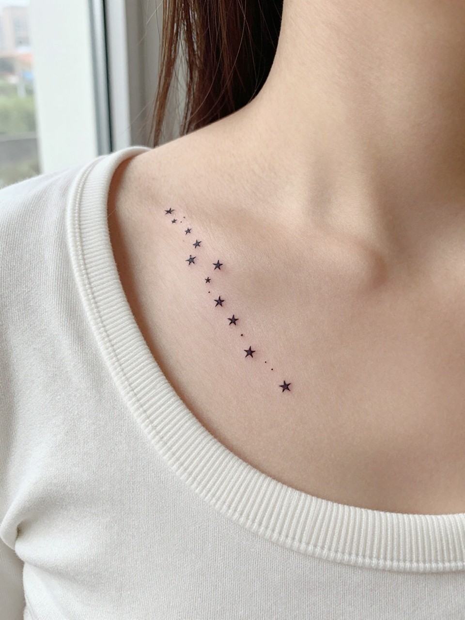 "Extreme macro close-up of a vertical line of tiny star tattoos on the middle chest. The fine, clean lines of the stars are the sharp focus against bare skin. She is wearing a soft, off-white cotton crewneck sweater. Soft, natural window light, clean and cheerful lifestyle aesthetic."