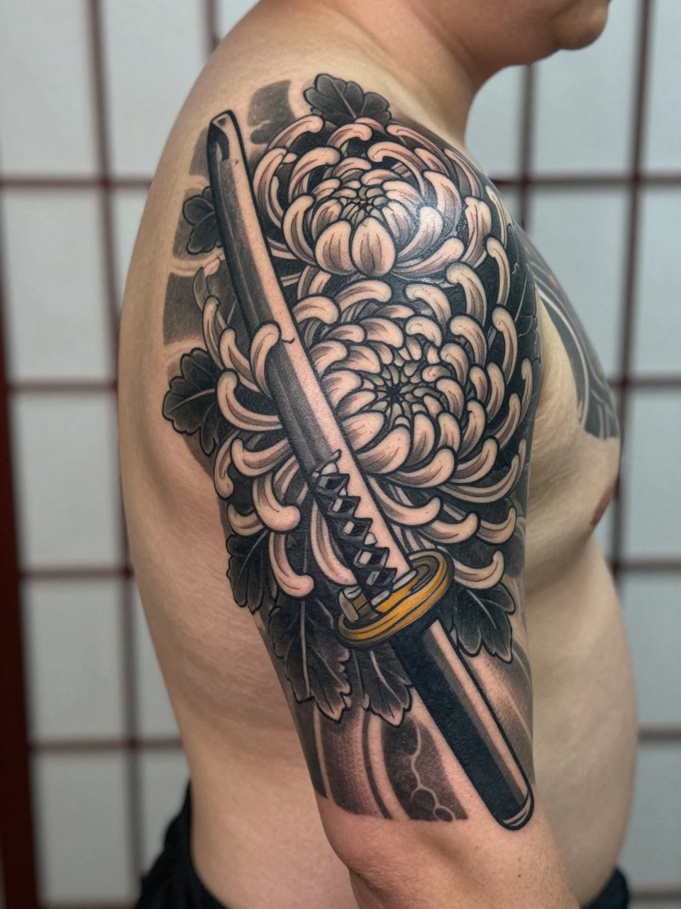 "design-focused close-up of a full back Japanese sword and chrysanthemum tattoo on a man, katana details crossing large chrysanthemum blooms, black and grey ink, bold traditional linework, soft shading, realistic skin texture, minimal blurred background (no watermarks on images)"