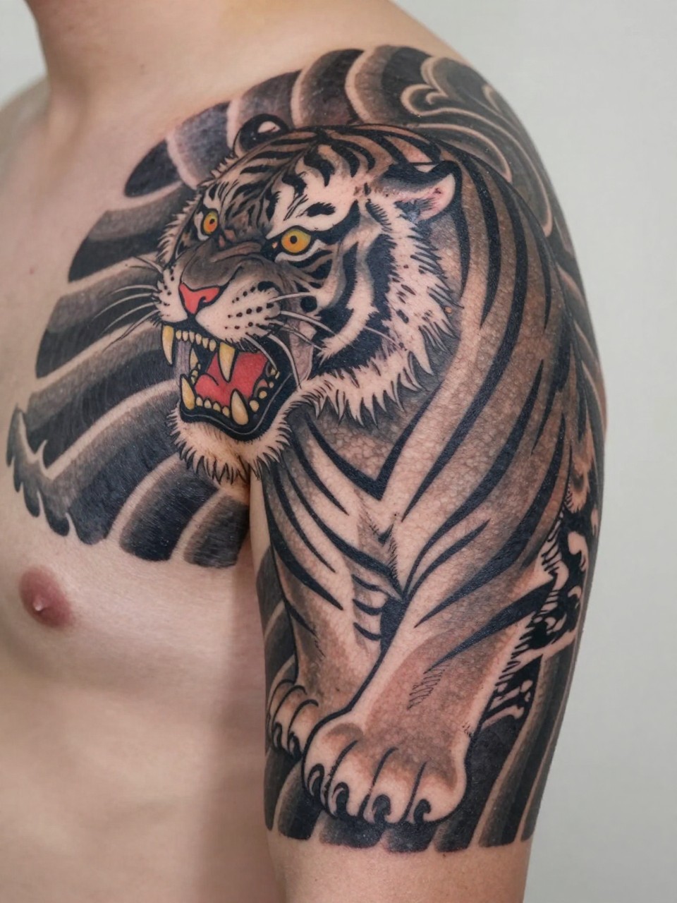 extreme close-up of a traditional Japanese tiger tattoo on the shoulder and upper arm, roaring tiger face, striped fur detail, black and grey ink, bold linework, smooth shading, realistic skin texture, minimal soft background, design-focused tattoo inspiration photography (no watermarks on images)