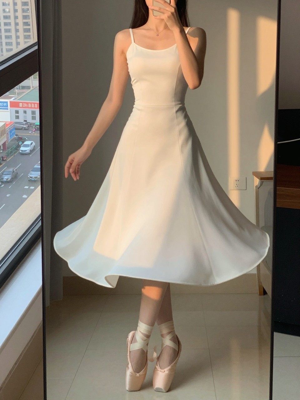 iPhone mirror selfie of a woman in a white fit-and-flare dress and ballet flats, twirling slightly, cropped at the neck so face doesn't show, in a city apartment, evening golden hour lighting, iPhone photo quality.