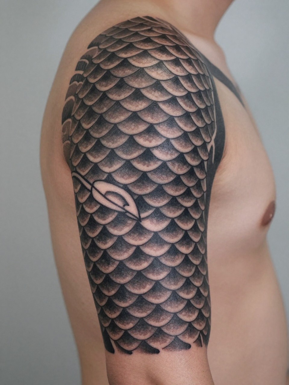 extreme close-up of a Japanese dragon scale armband tattoo on a man's upper arm, repeating scale pattern wrapping around the arm, black and grey ink, strong texture, crisp traditional-inspired linework, realistic skin texture, soft minimal background, design-focused tattoo inspiration photography (no watermarks on images)