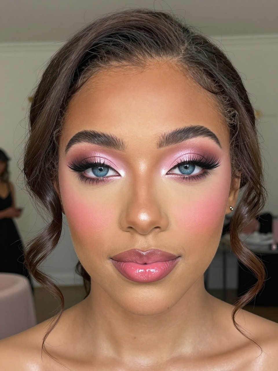 Super realistic close-up beauty portrait of a black young woman with blue eyes wearing lovely prom makeup, featuring a pink champagne halo eye with rosy taupe inner and outer corners, soft mauve crease blending, bright pink champagne center-lid shimmer, soft volumized lashes, fresh rose-pink blush, soft champagne-pearl highlight, rosy pink glossy lips, polished brows, realistic skin texture with a radiant prom glow, shot from a front-facing beauty portrait, with soft diffused flash-friendly lighting that clearly reveals the halo shimmer, blue eyes, and glossy lips, romantic curled hairstyle, blurred elegant ballroom background, feminine modern beauty photography, latest iPhone photo quality.