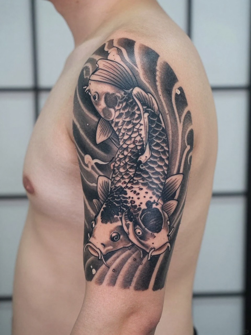 design-focused close-up of a Japanese koi and water armband tattoo on a man's upper arm, detailed koi fish moving through flowing water band, black and grey ink, crisp traditional linework, smooth shading, realistic skin texture, minimal blurred background, modern tattoo inspiration photo (no watermarks on images)