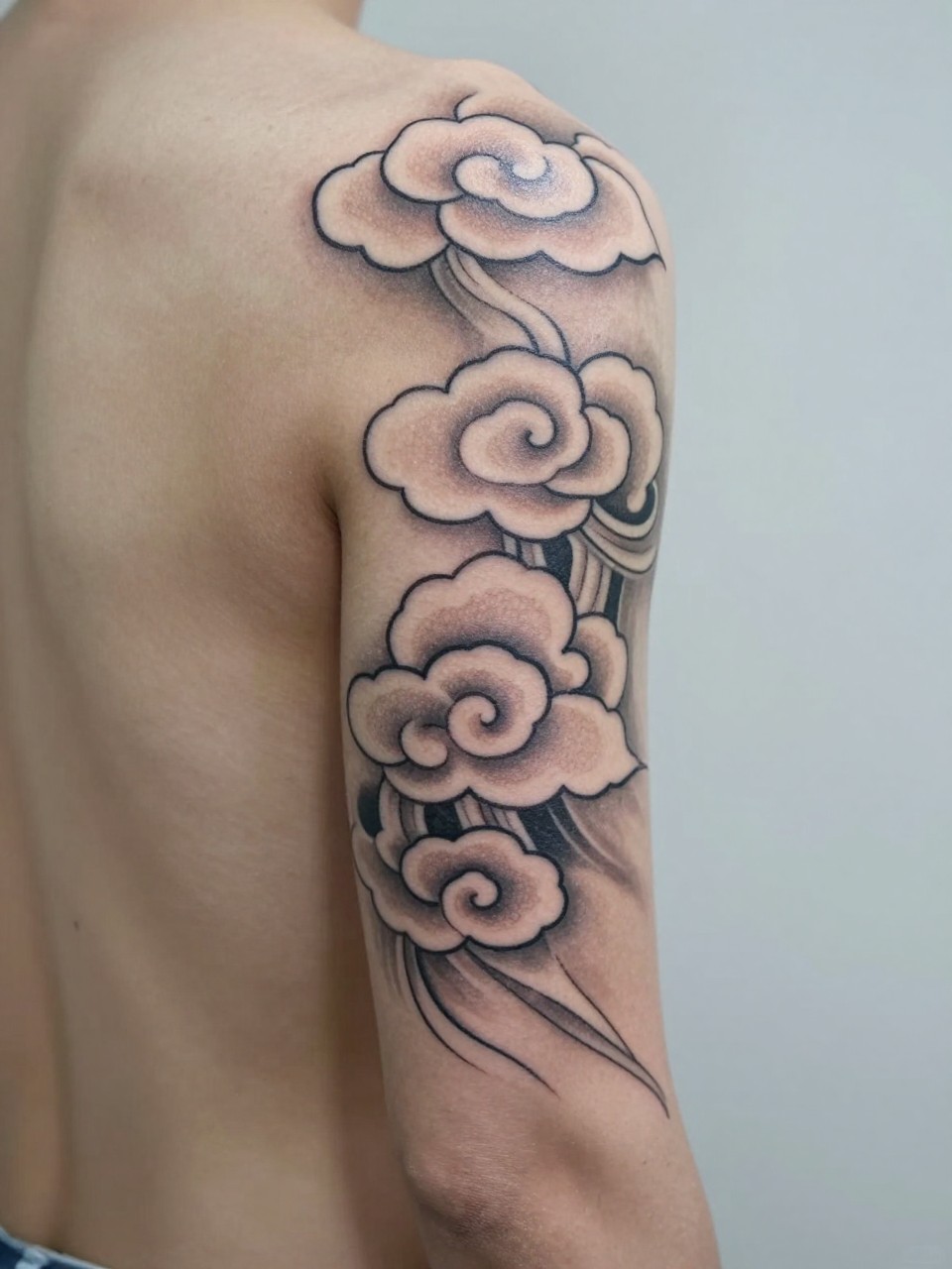 close-up of a vertical Japanese cloud tattoo along the spine, layered traditional cloud forms flowing down the back, black and grey ink, clean linework, soft shading, realistic skin texture, open-back top visible, design-focused close-up, blurred neutral background, modern tattoo photography (no watermarks on images)