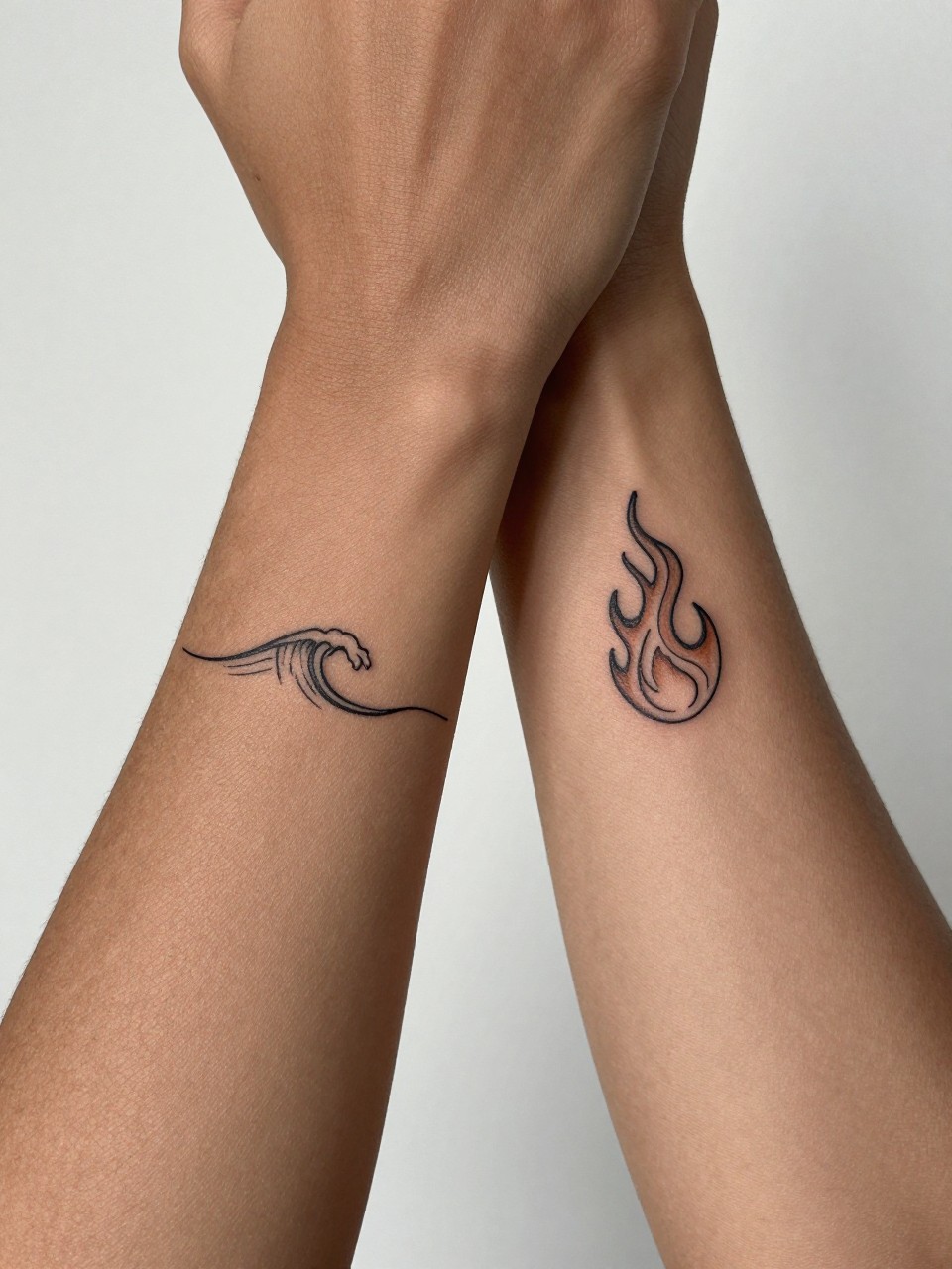 "extreme close-up of matching wave and flame tattoos on dark skin, one tiny wave on one wrist and one small flame on the other, clean black ink, fine line minimalist style, realistic skin texture, soft minimal background, design-focused tattoo inspiration photography (no watermarks on images)"