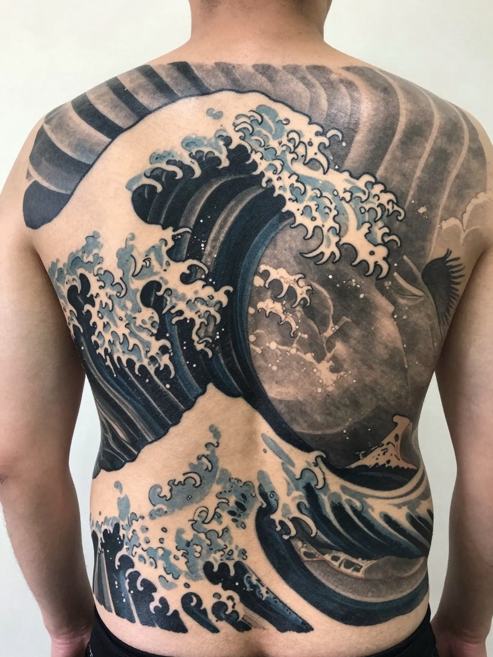 close-up of a full back Japanese wave tattoo panel on a man, large layered cresting waves across the entire back, black and grey ink, bold traditional linework, smooth shading, balanced composition, realistic skin texture, design-focused tattoo visibility, minimal background (no watermarks on images)