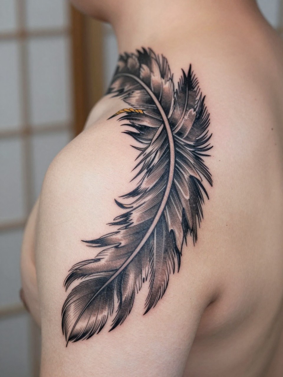 close-up of a traditional Japanese phoenix feather tattoo on the back of the hand, layered feather detail, black and grey ink, soft shading, elegant bold linework, realistic skin texture, design-focused close-up, blurred neutral background, modern tattoo photography (no watermarks on images)
