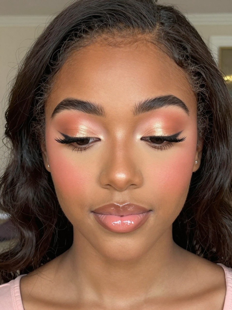 Super realistic close-up beauty portrait of a black teenage wearing classy soft glam prom makeup, featuring soft peach matte crease shading, peach shimmer across the lids, natural fluttery lashes, fresh peach-pink blush, light gold highlight on the cheekbones, milky nude peach glossy lips, softly polished brows, realistic skin texture with a fresh radiant glow, shot from a front-facing beauty portrait, with warm flattering prom lighting that clearly reveals the peach tones, skin glow, and glossy lips, romantic soft curls, blurred elegant ballroom background, feminine modern beauty photography, latest iPhone photo quality.