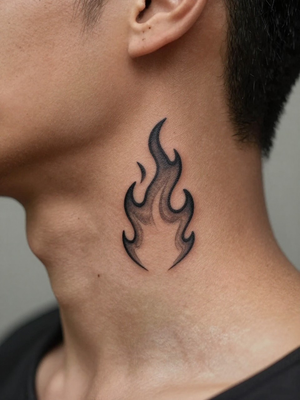 "close-up of a small flame tattoo on deep brown skin at the neck, clean black ink, crisp flame outline with soft shading, minimalist masculine style, realistic skin texture, fresh haircut visible, design-focused close-up, soft blurred background, modern tattoo photography (no watermarks on images)"