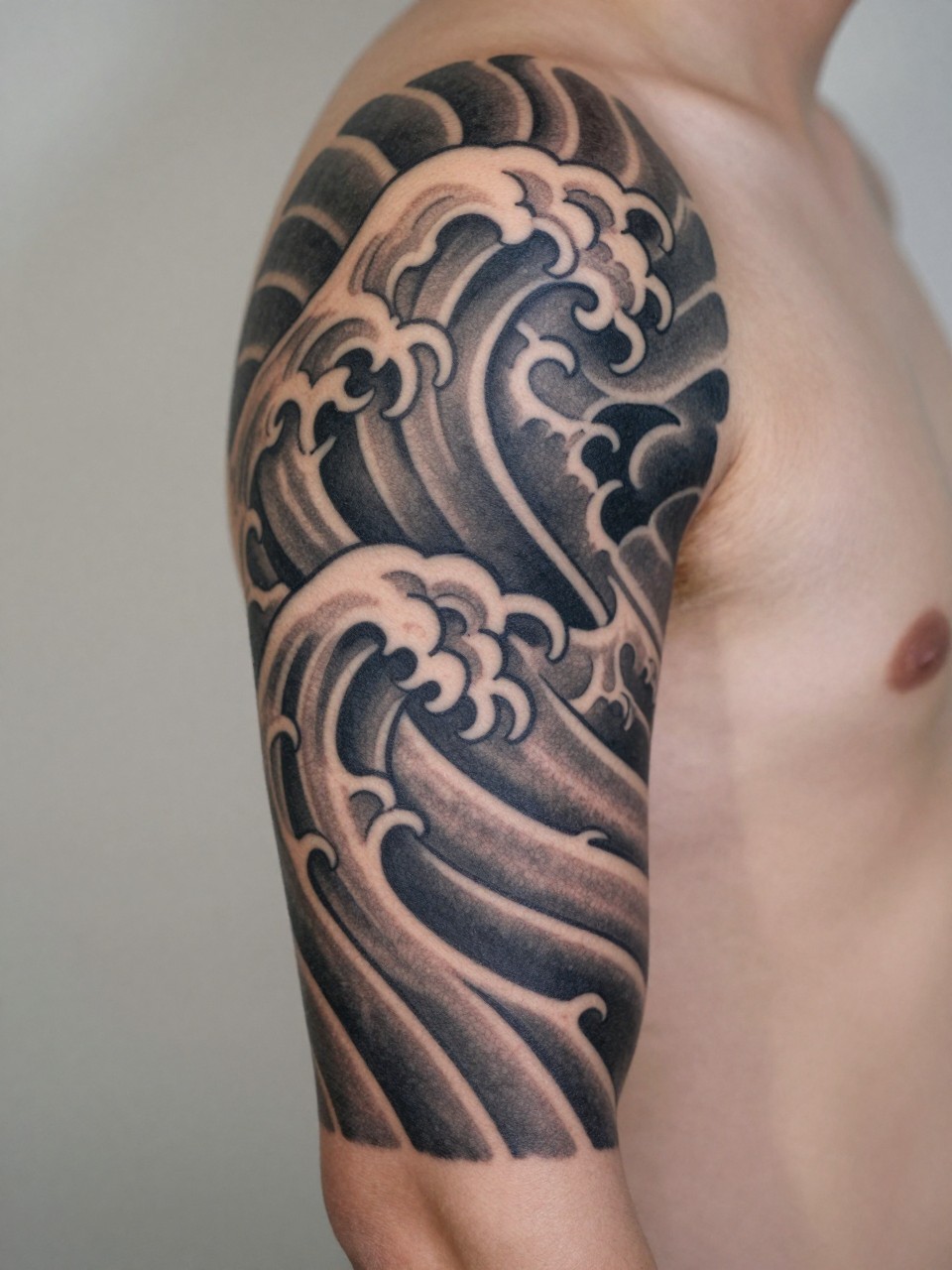 macro shot of a clean Japanese half sleeve wave tattoo on the arm, layered traditional wave forms, black and grey ink, crisp linework, smooth shading, balanced composition, realistic skin texture, tight crop, design-first tattoo image, soft neutral background, tattoo inspiration image (no watermarks on images)