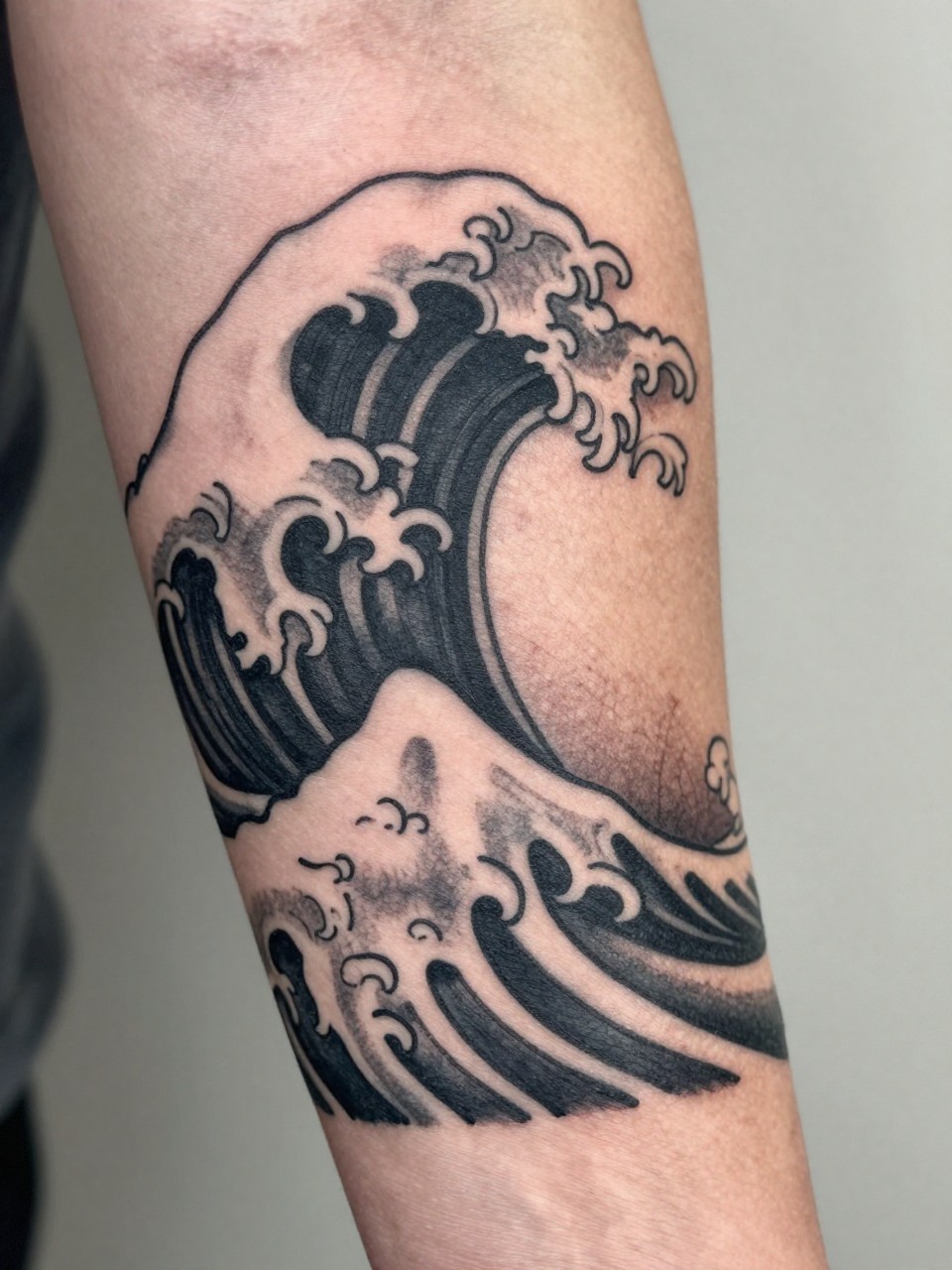 macro shot of a clean Japanese wave band tattoo wrapping around the forearm, repeating traditional wave pattern, black and grey ink, crisp linework, soft shading, realistic skin texture, tight crop, design-first tattoo composition, soft neutral background, tattoo inspiration image (no watermarks on images)