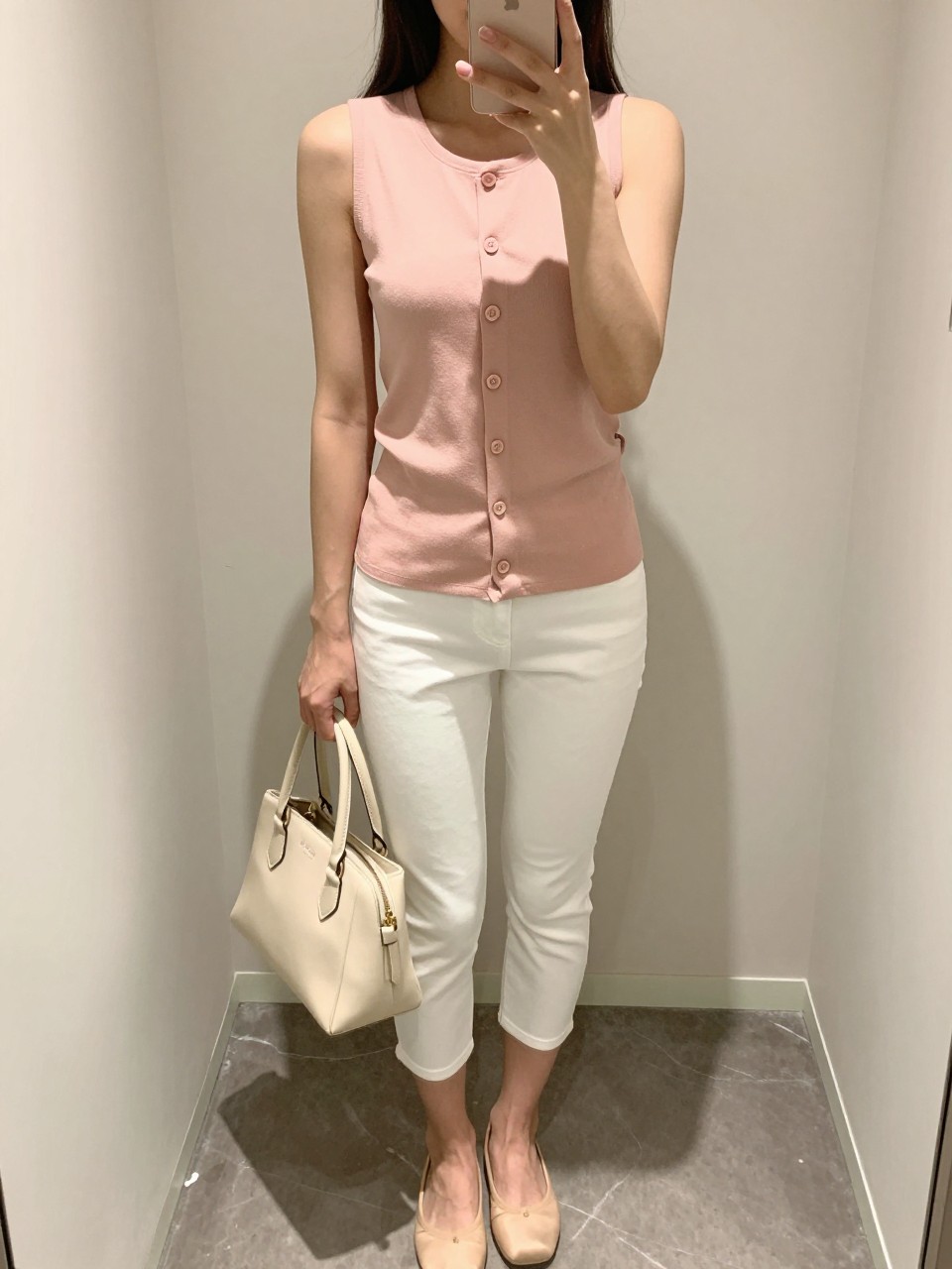 IMAGE_PROMPT: mirror selfie of a woman wearing a soft pink button-front sleeveless top, white slim capri pants, nude ballet flats, cream mini handbag, and glossy pink lip makeup, clearly showing the same clothing items listed in the Outfit Pieces section, holding a phone in front of a mirror, cropped at the NECK so the face does not show, relaxed casual selfie pose, in a minimal dressing room, soft indoor lighting, with handbag hanging on a door handle, latest iPhone photo quality.