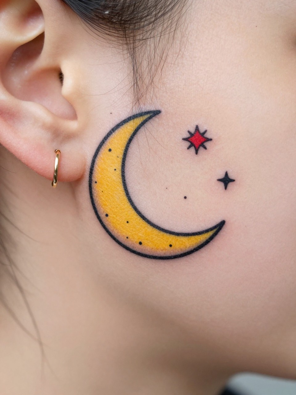 Image Prompt: "Macro shot of an American traditional crescent moon tattoo behind the ear, bold black outline, soft yellow moon fill, tiny red and black stars around it, minimal dotwork accents, small tattoo size, clean skin texture, simple gold earring nearby, close-up design-first composition"