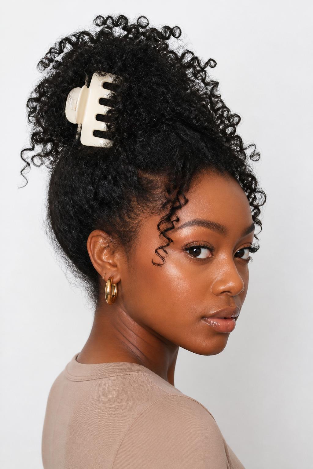 Image Prompt:
A realistic beauty portrait of a black woman with medium-long natural curly hair styled into a messy claw clip puff, curls gathered upward and secured with a large matte cream claw clip, defined curls spilling softly at the top, loose tendrils around the forehead, warm brown skin, gold hoop earrings, fitted beige top, clean bright studio background, natural texture hairstyle inspiration, high-resolution DSLR photo, no text, (no watermarks on images)