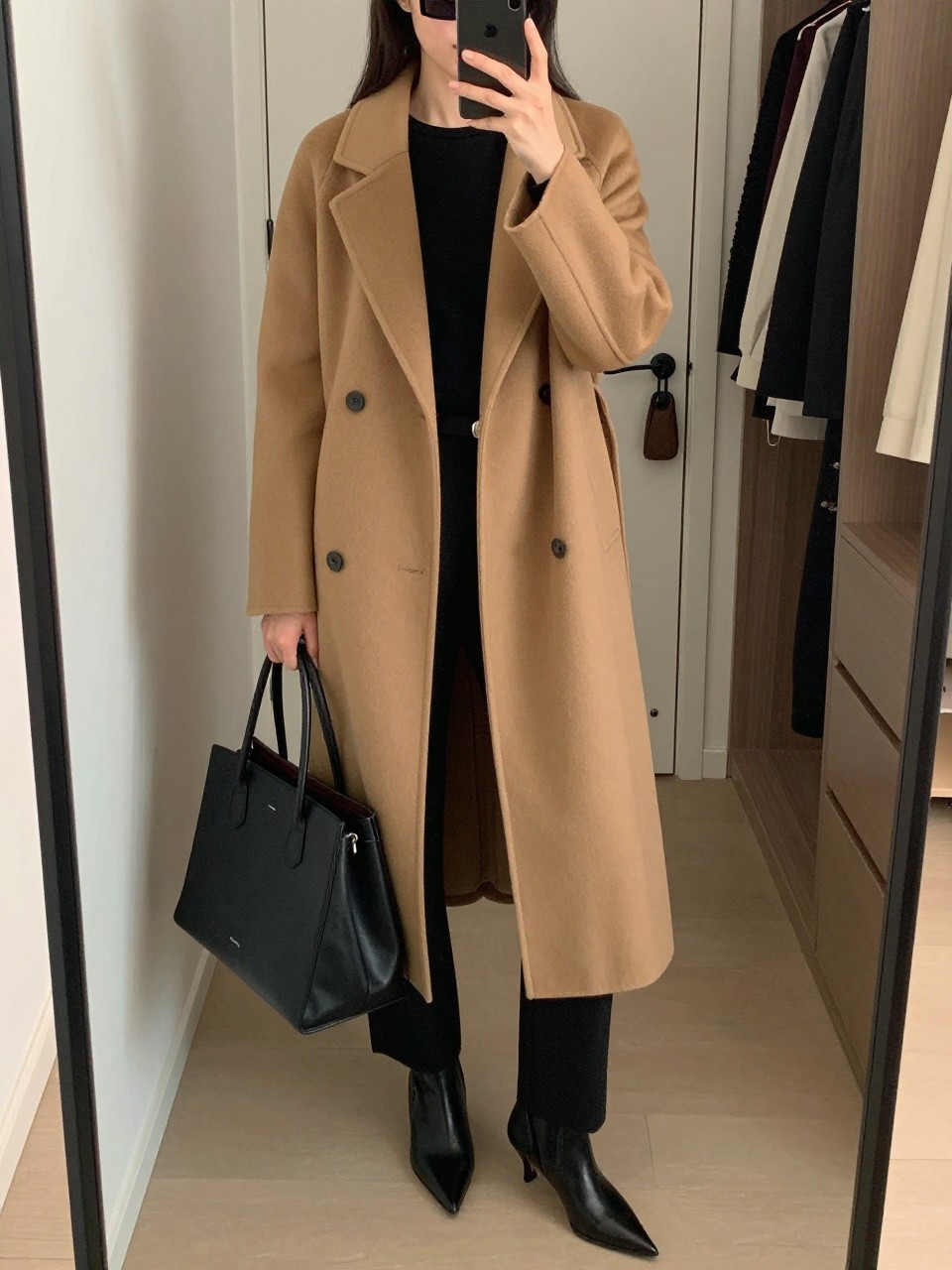 Outfit Image Prompt:
mirror selfie of a woman wearing a camel tailored maxi coat, black fitted long-sleeve top, black straight-leg trousers, black pointed ankle boots, black rectangular sunglasses, and a structured black leather tote bag, holding a phone in front of a mirror, cropped at NECK so the face does not show, relaxed polished city selfie pose, in a walk-in closet mirror, soft indoor lighting, with an open closet with clothes visible and a handbag hanging on a door handle, realistic latest iPhone photo quality, NYC high fashion minimal outfit.