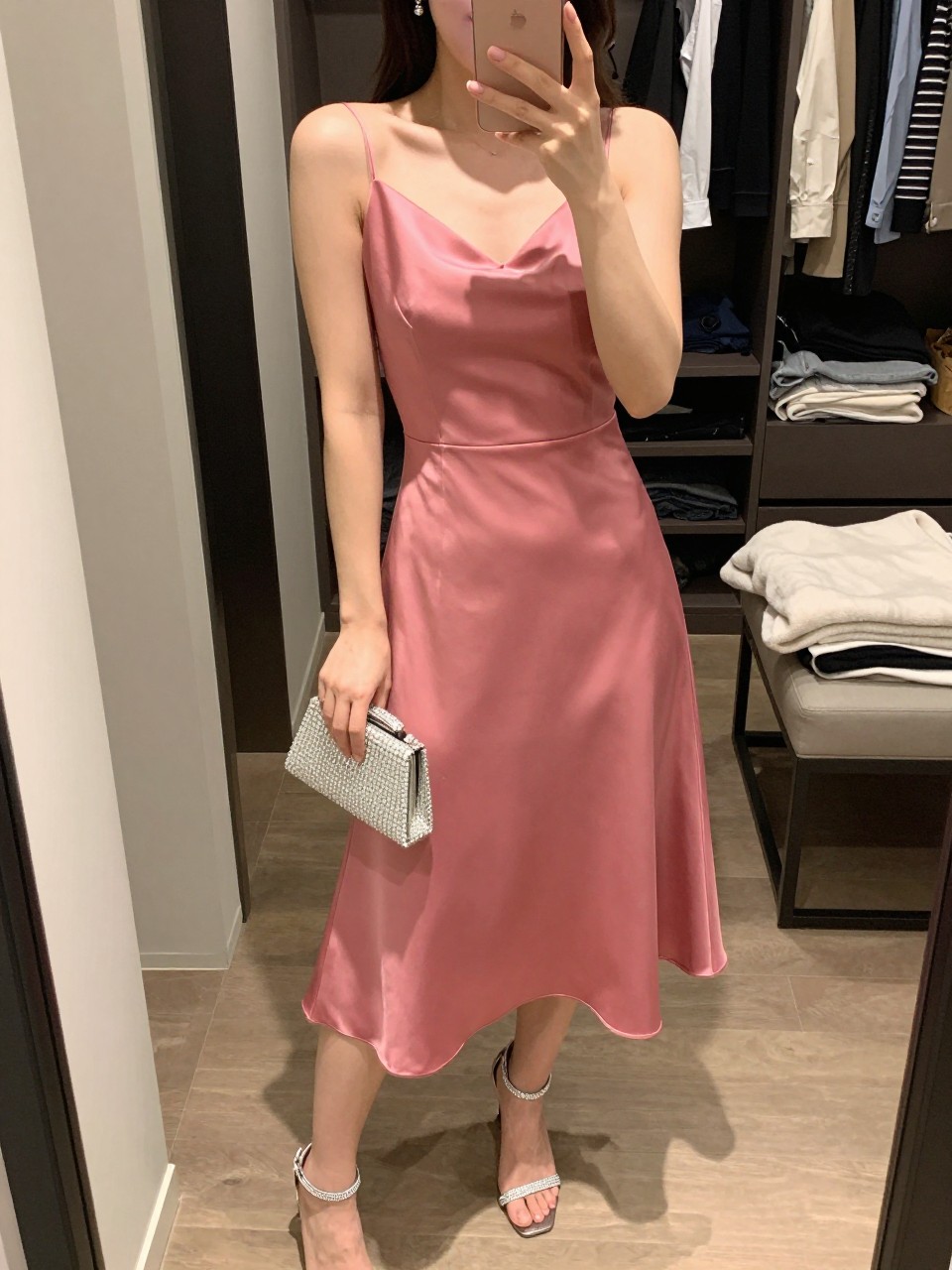 Image Prompt

mirror selfie of a woman wearing a raspberry pink satin A-line midi dress, rhinestone ankle-strap sandals, small silver drop earrings, crystal-trim mini clutch, and smooth waves with soft mauve lipstick, clearly showing the same clothing items, colors, fabrics, and accessories listed in the Outfit Pieces section, holding a phone in front of a mirror, cropped at NECK so the face does not show, with a relaxed casual selfie pose, in a walk-in closet mirror, soft indoor lighting, including open closet with clothes visible and folded blanket on a chair, latest iPhone photo quality.
