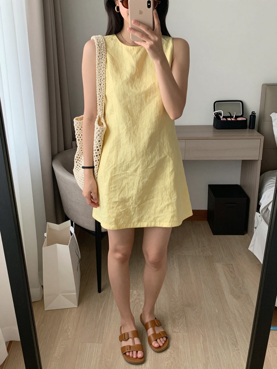 Outfit Image Prompt:
mirror selfie of a woman wearing a soft yellow linen mini dress, tan leather slide sandals, a cream crochet shoulder bag, gold hoop earrings, and slim brown sunglasses, holding a phone in front of a mirror, cropped at NECK so the face does not show, relaxed casual selfie pose, in a cozy bedroom mirror setup, natural window light, with shopping bags beside a chair and a makeup bag on the counter, realistic latest iPhone photo quality, casual sunny vacation outfit.
