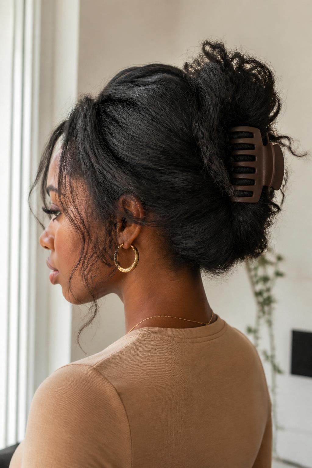Image Prompt:
A realistic hairstyle photo of a black woman with medium-length textured natural hair styled into a messy claw clip updo, hair gathered at the back with a large matte brown claw clip, soft volume at the crown, textured ends spilling upward, gold hoop earrings, warm beige top, clean indoor background, bright window light, natural hair updo inspiration, high-resolution DSLR photography, no text, (no watermarks on images)