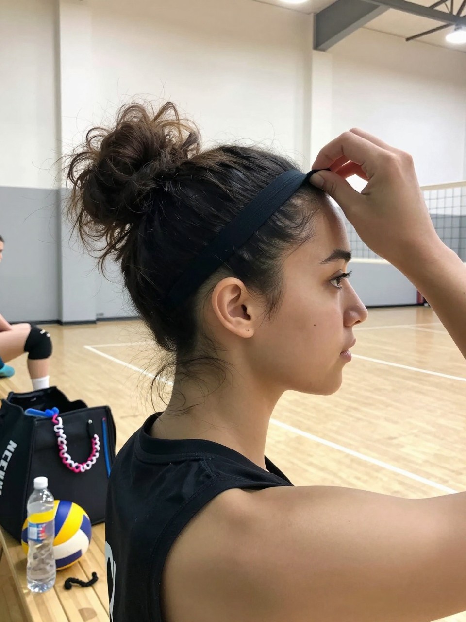 Image prompt

Photo of a woman wearing a secure high curly bun with a slim black sports headband holding back her hairline, side profile view inside a bright volleyball gym, soft court lighting, containing a small lived-in detail such as knee pads on the bleachers, a volleyball beside her sports bag, and a spare scrunchie looped around her water bottle, realistic pre-match moment, latest iPhone photo quality.