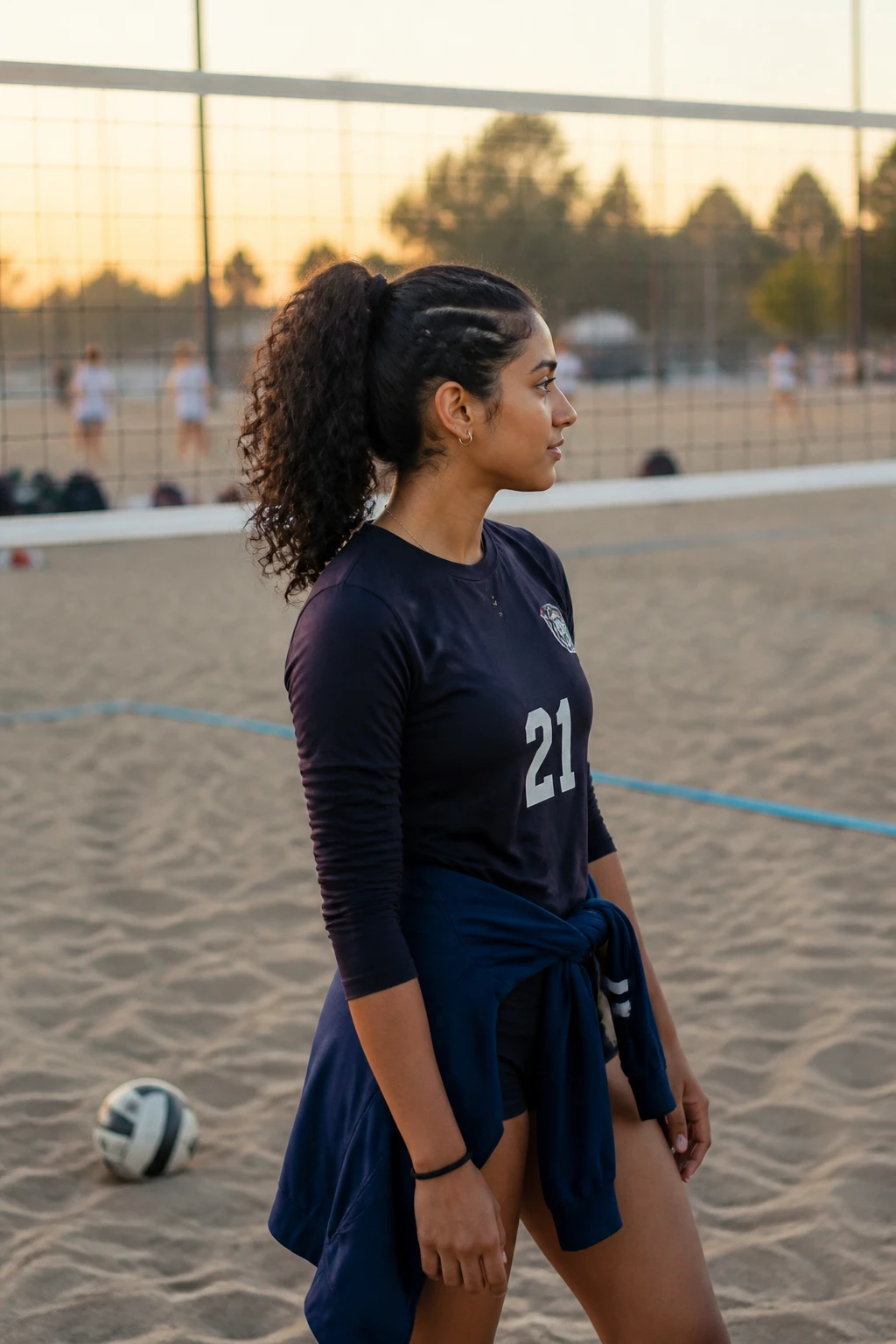 Image prompt

Photo of a South Asian woman wearing a high curly volleyball ponytail with two narrow braids sweeping upward from each side into the base, side profile view near a softly blurred outdoor volleyball court, golden hour glow, containing a small lived-in detail such as a team jacket tied around her waist, a volleyball near her feet, and a spare elastic on her wrist, realistic candid sports photograph, latest iPhone photo quality.