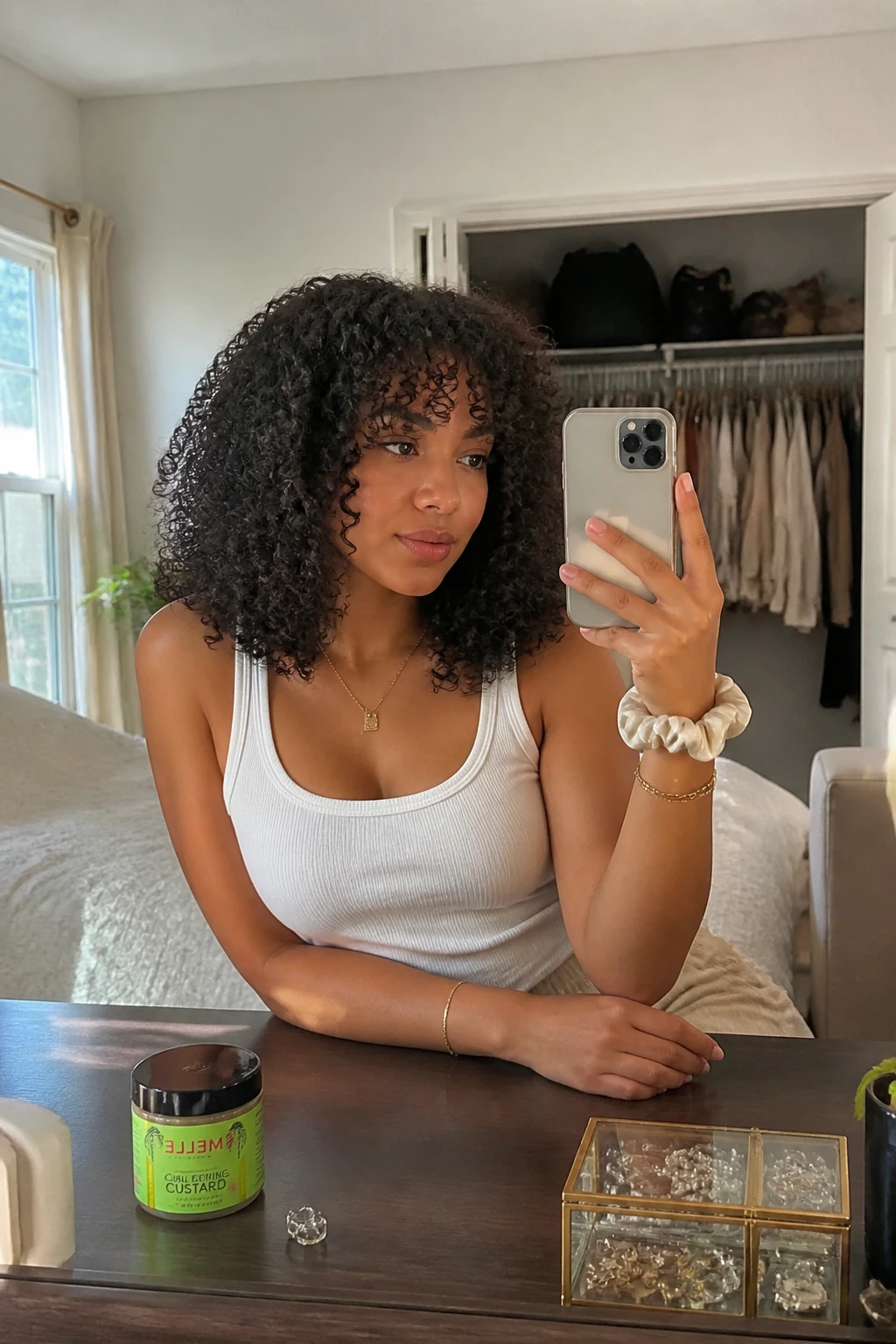 Image prompt
Photo of a woman wearing medium-length 3B curls in a softly rounded cut with springy ringlets, light face-framing layers beginning near the cheekbones, and natural volume around the crown, candid mirror selfie in a sun-drenched bedroom, natural window light, containing a small lived-in detail such as a curl cream jar on the dresser, a silk scrunchie on her wrist, and a slightly open closet behind her, realistic getting-ready moment, latest iPhone photo quality.