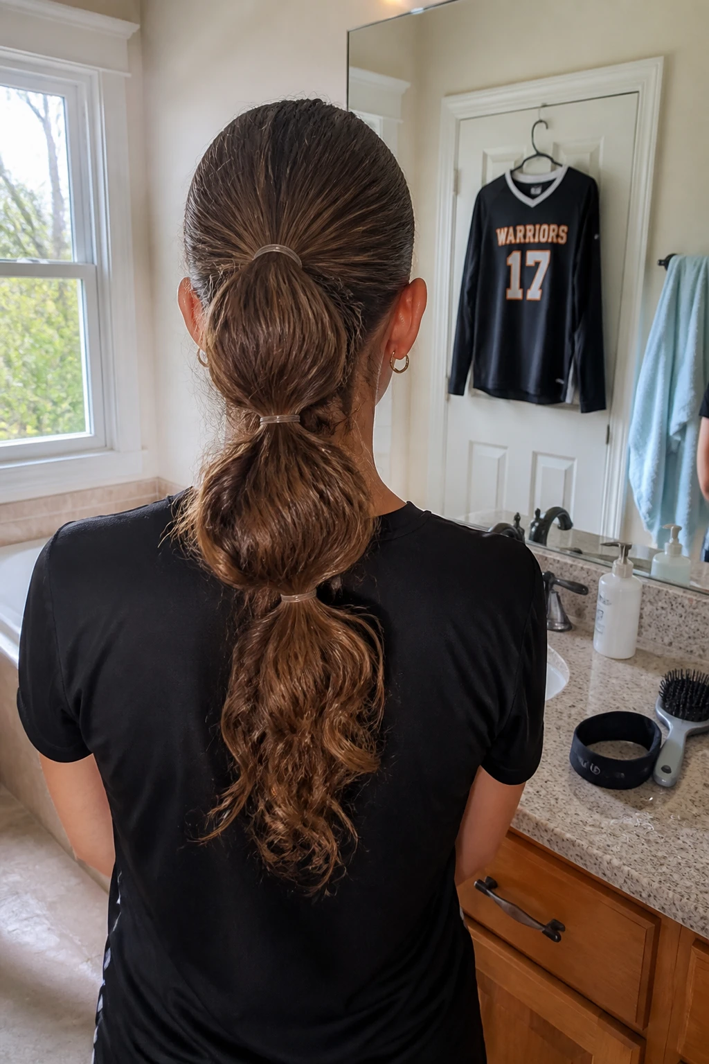Image prompt

Photo of a woman wearing a mid-height curly bubble ponytail with three softly rounded sections and a smooth athletic base, back-of-head view showing the full ponytail design, standing beside a bathroom vanity before volleyball practice, natural window light, containing a small lived-in detail such as clear elastics on the counter, a volleyball jersey hanging from the door, and a sports headband beside a hairbrush, realistic getting-ready moment, latest iPhone photo quality.