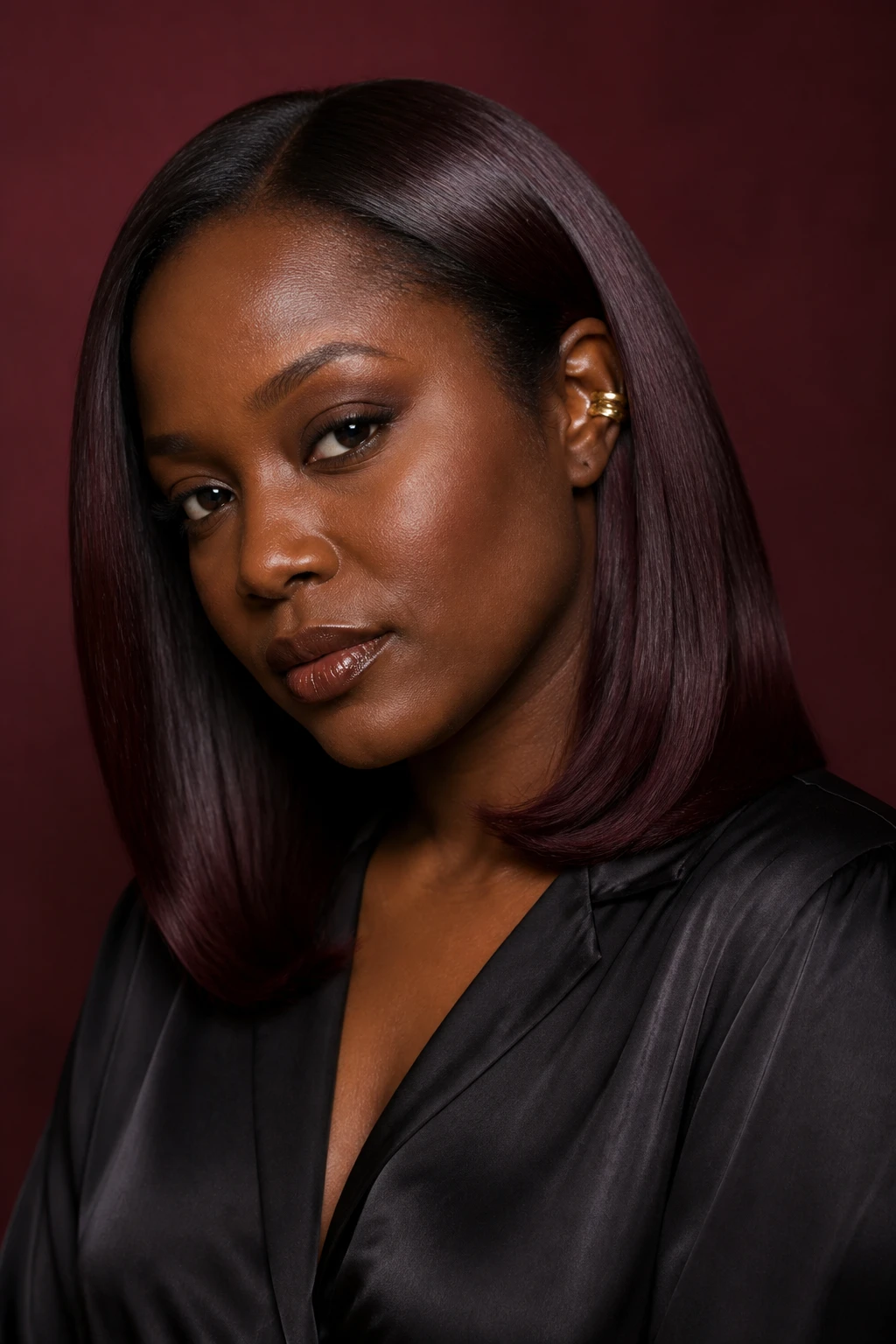 A realistic editorial portrait of a Black woman with rich dark skin wearing a smooth shoulder-length silk press, black cherry espresso color drench, near-black espresso roots, deep cherry-brown lengths with subtle merlot and plum undertones, color applied evenly without obvious highlights, berry reflection visible mainly along the curved mid-lengths under direct light, no vivid red or purple streaks, slight inward bend at the ends, natural hairline, black satin blouse, gold ear cuff, muted burgundy studio wall, controlled softbox light, realistic shine and natural skin texture.