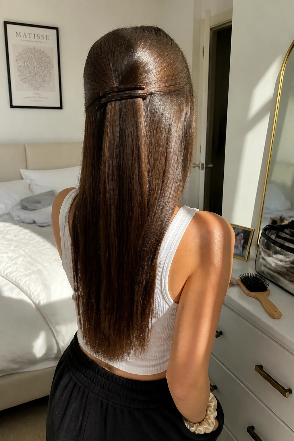 Image prompt
Photo of a woman wearing long straight hair in a half-up style secured with two slim matching barrettes placed side by side at the back, back-of-head view highlighting the accessory placement and smooth lengths, standing in a sun-drenched bedroom, natural window light, containing a small lived-in detail such as a paddle brush on the dresser, a makeup bag nearby, and a silk scrunchie on her wrist, realistic getting-ready moment, latest iPhone photo quality.