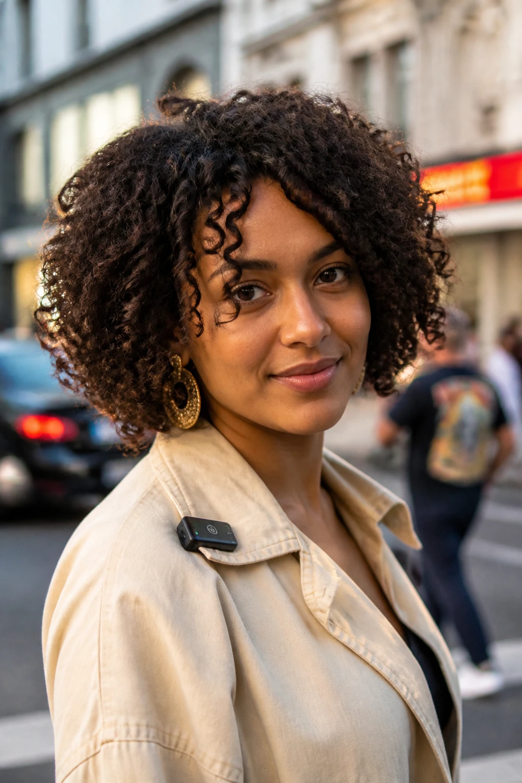 Image prompt
Photo of a woman wearing a short voluminous 3B curly bob with deep internal layers, soft lift at the crown, and full springy ringlets framing the face, front three-quarter view against a softly blurred city street background, golden hour glow, containing a small lived-in detail such as statement earrings and a tiny clip attached to her jacket collar, realistic candid photograph, latest iPhone photo quality.
