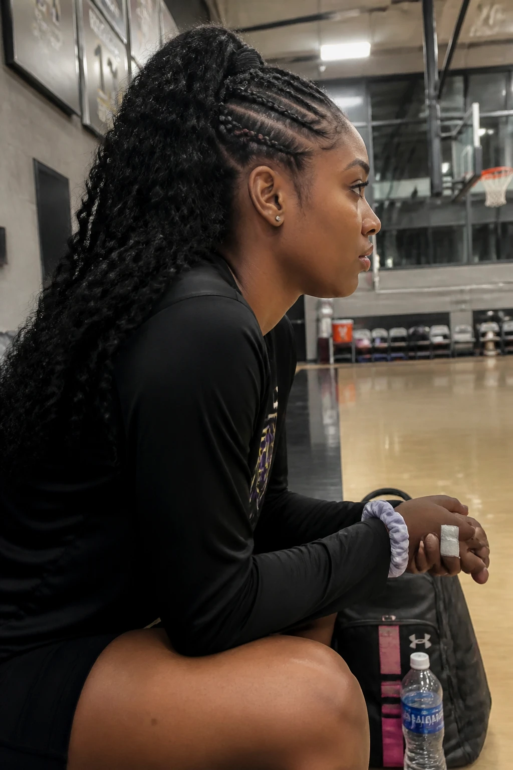 Image prompt
Photo of a Black woman wearing a sporty braided mohawk ponytail with two neat side cornrows, a full central section of curls, and a secure high ponytail at the crown, side profile view inside a modern indoor training gym, soft court lighting, containing a small lived-in detail such as athletic tape around one finger, a water bottle near a sports bag, and a spare scrunchie on her wrist, realistic game-day preparation, latest iPhone photo quality.
