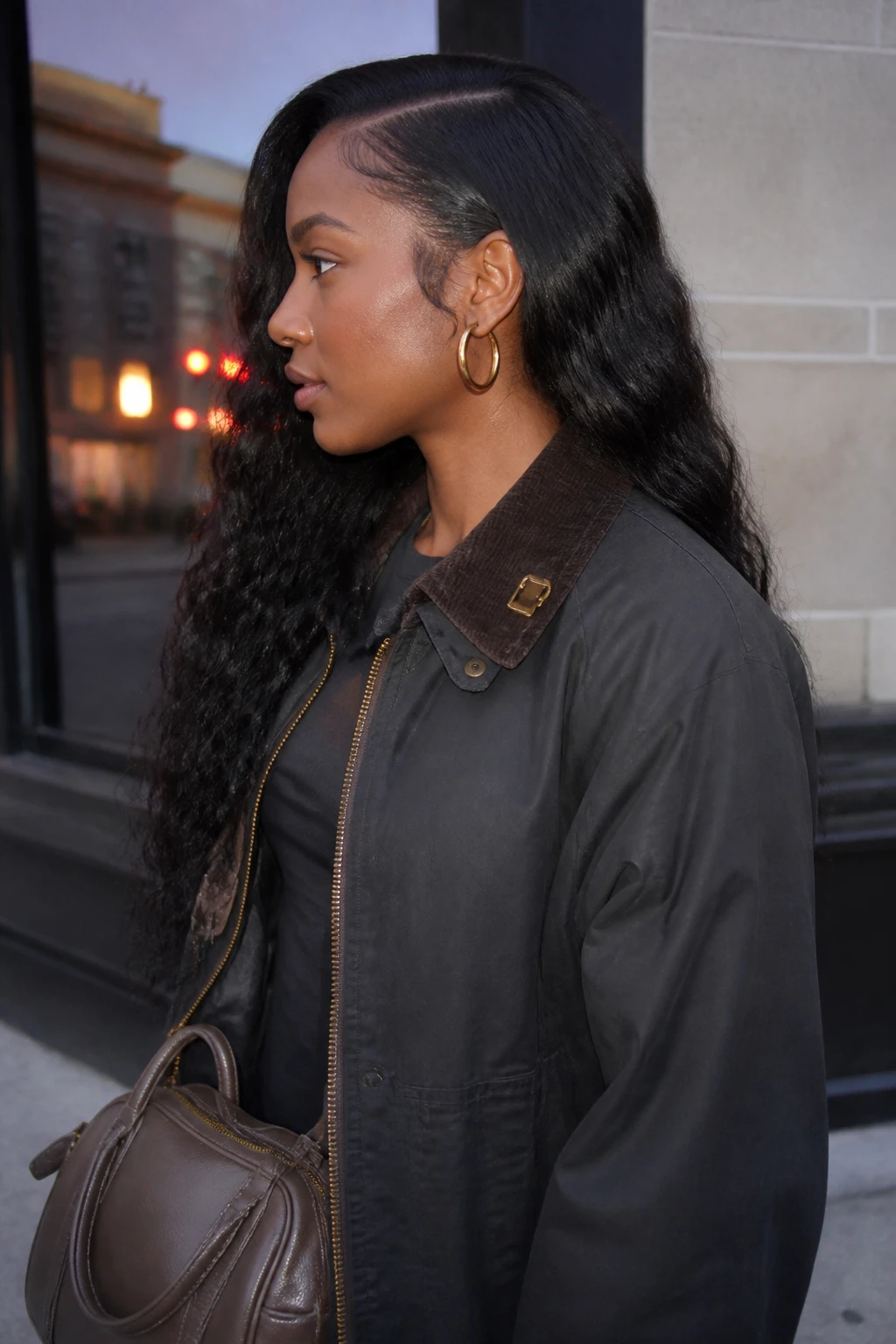 Image prompt
Photo of a Black woman wearing a long water wave sew-in with a deep side part, glossy loose curls sweeping over one shoulder, and the lighter side tucked neatly behind the ear, side profile view against a softly blurred city street background, golden hour glow, containing a small lived-in detail such as gold hoop earrings, a slim hair clip attached to her jacket collar, and a small handbag near her hip, realistic candid photograph, latest iPhone photo quality.
