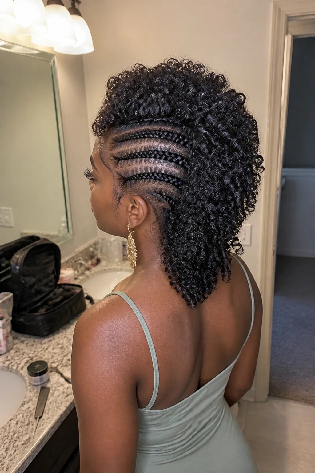 Image prompt
Photo of a Black woman wearing a curly mohawk with four neat cornrows on each side and a full line of springy natural curls through the centre, back three-quarter view highlighting the braid pattern and curl texture, standing at a bathroom vanity mirror, soft indoor lighting, containing a small lived-in detail such as edge gel and a rat-tail comb on the counter, a makeup bag nearby, and statement earrings peeking through, realistic getting-ready moment, latest iPhone photo quality.