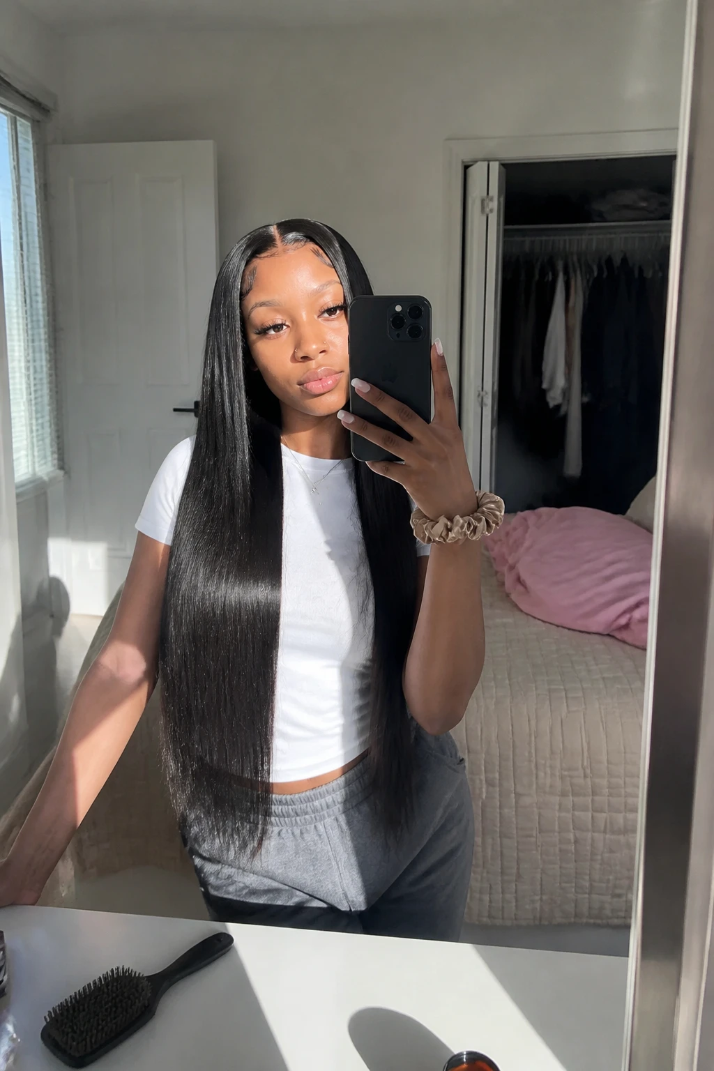 Image prompt

Photo of a woman wearing a sleek middle-part waist-length straight weave with smooth glossy strands and neatly styled edges, candid mirror selfie showing the full hair length, standing in a sun-drenched bedroom with a slightly open closet behind her, natural window light, containing a small lived-in detail such as a silk scrunchie on her wrist and a hairbrush resting on a nearby dresser, realistic getting-ready moment, latest iPhone photo quality.