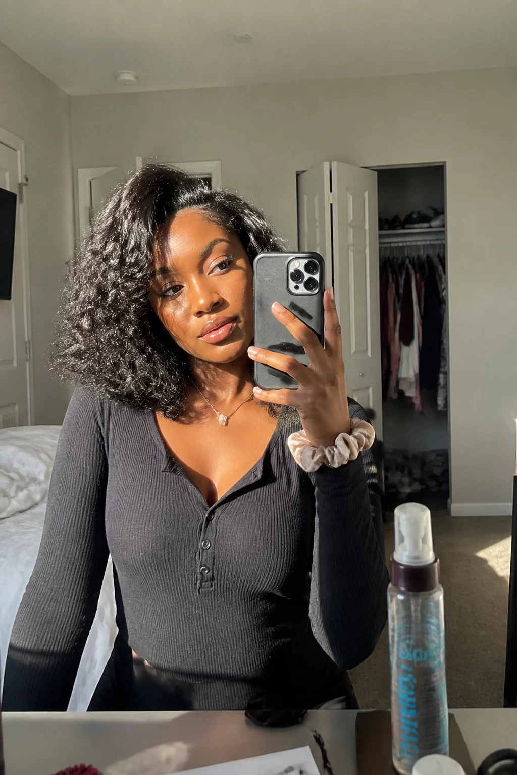 Image prompt
Photo of a Black woman wearing a shoulder-length layered curly sew-in with soft rounded volume, defined medium-sized curls, a natural-looking side part, and light face-framing layers around the cheeks, candid mirror selfie in a sun-drenched bedroom, natural window light, containing a small lived-in detail such as a curl mousse bottle on the dresser, a silk scrunchie on her wrist, and a slightly open closet behind her, realistic getting-ready moment, latest iPhone photo quality.